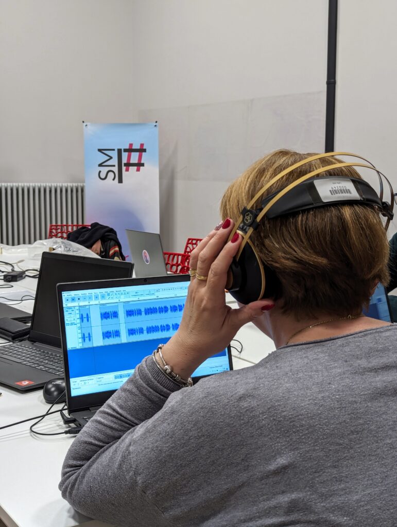 Una donna di spalle lavora sul computer a una traccia audio.