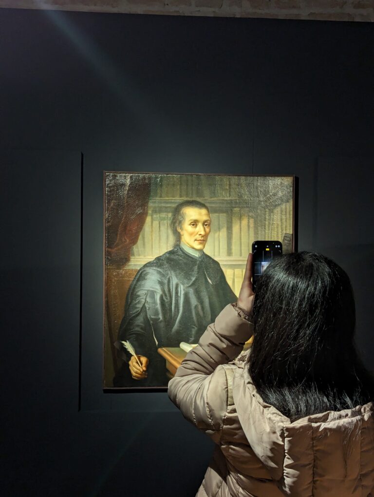 Una ragazza di spalle sta fotografando un dipinto.